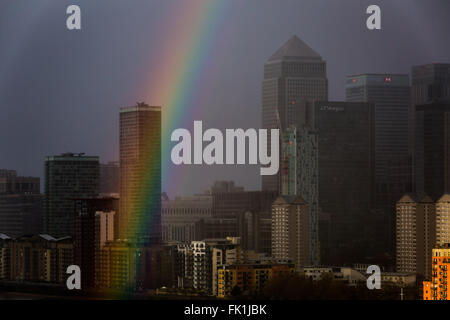 London, UK. 5th March, 2016. UK Weather: Colourful rainbow breaks during a sunset rainstorm over Canary Wharf business park buildings Credit:  Guy Corbishley/Alamy Live News Stock Photo