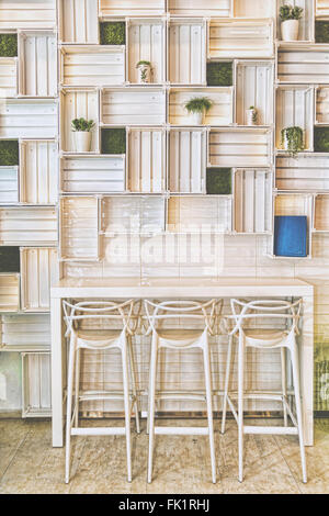Bar Stools in Modern Caffe or Home Kitchen Wall. Nice Hotel Lounge Bar with White Three Barstool Seats and Shelfs, Table and Flo Stock Photo