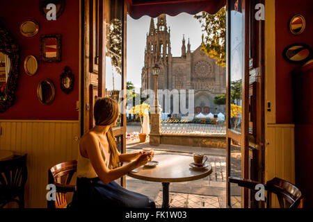 AGAETE, GRAN CANARIA island, SPAIN - DECEMBER 13, 2015: View on San Juan Bautista church from El parque cafe with woman sitting Stock Photo
