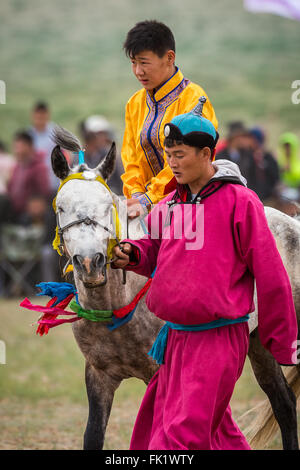 Man leading a boy on a horse to the starting line. Stock Photo