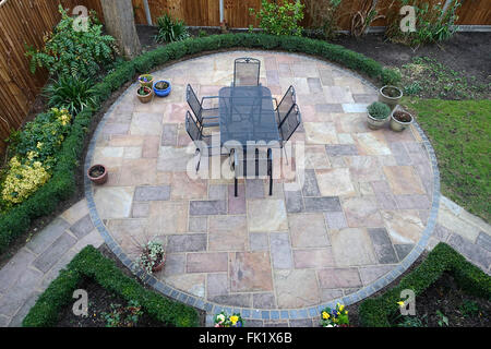 Circular garden patio with metal table and chairs in the middle Stock Photo