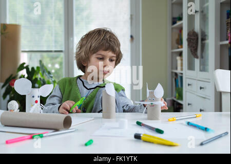 Little boy being creative making homemade paper toys. Supporting creativity, learning by doing, learning through experience. Stock Photo