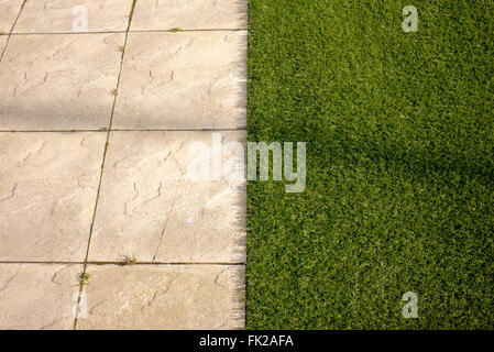 Artificial grass / astro turf meets paving slabs on a new build housing estate. Bicester, Oxfordshire, England Stock Photo