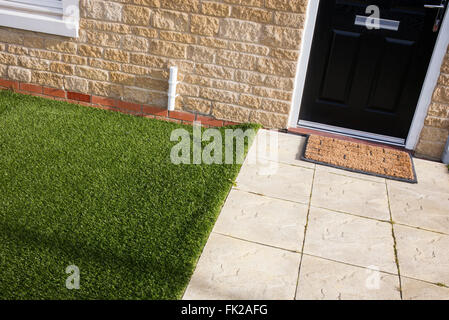 Artificial grass / astro turf meets paving slabs on a new build housing estate. Bicester, Oxfordshire, England Stock Photo