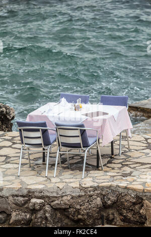 Laid table and chairs at a restaurant right by the sea. Stock Photo