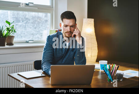 Worried entrepreneur young man working at desk on laptop looking serious Stock Photo