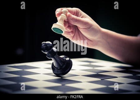 Close-up image of a hand moving a chess piece and defeating the challenger. Stock Photo