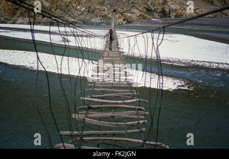 Man crossing the Hussaini bridge in Passu, old suspension bridge, above the Hunza River in Hunza Valley, Pakistan. Stock Photo