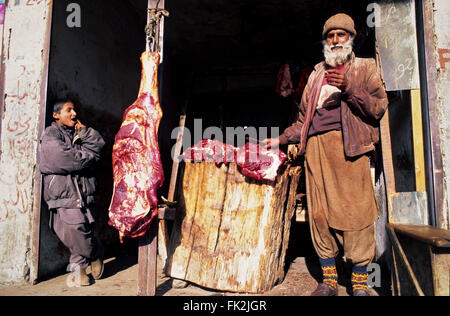 A butcher from Gilgit (Hunza Valley, Pakistan) stands at his shop displaying animal meats. Stock Photo