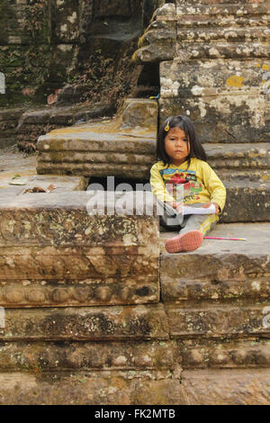 girl sitting on floor reading book in angor wat, cambodia Stock Photo