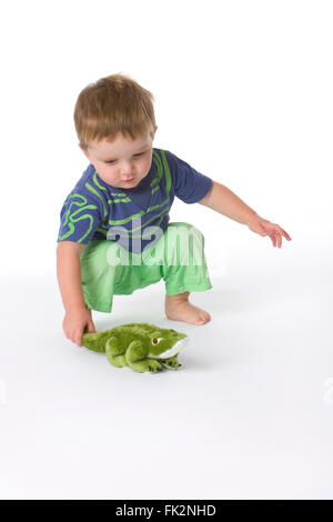 Toddler Boy playing with a toy crocodile on white background Stock Photo