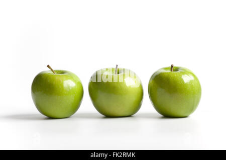 Three green shiny Granny Smith apples on a row on white background Stock Photo