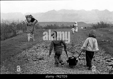 Near Zakho, northern Iraq, Kurdistan. April 1991.Kurdish children and families carry their belongings towards mountains which mark the border with Turkey. They were escaping as refugees after  the failed uprising by Kurds against forces of Saddam Hussein's government. Stock Photo