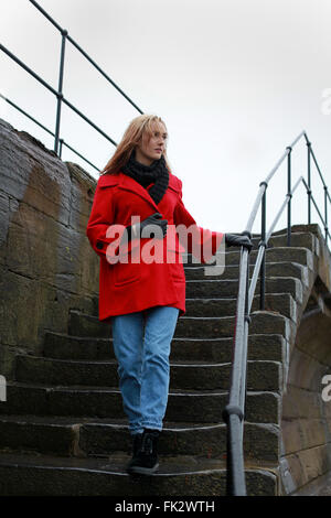 Young woman walking down some old steps on a wet winters day Stock Photo