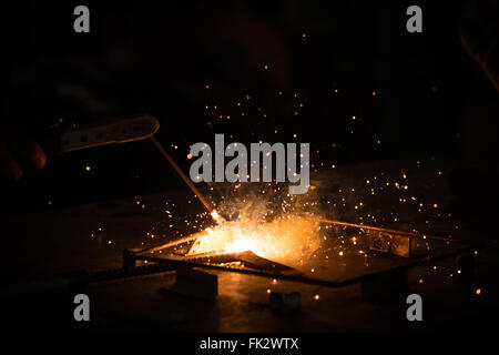 Welding, metal working on dark background, with golden bokeh and flare of sparks. Technician workshop, manufacturing industry, or construction worker Stock Photo