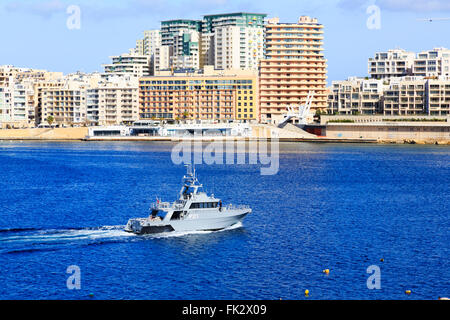 Maltese Navy patrol boat leaving Grand Harbour with Sliema hotels in the background.Valletta, Malta Stock Photo