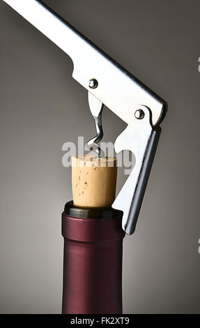 Closeup of a modern metal cork screw pulling the cork from a wine bottle.