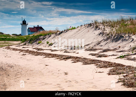 Race Point lighthouse lies behind sand dunes on Cape Cod, in Massachusetts, as a rain storm approaches. It offers overnight lodging for tourists. Stock Photo