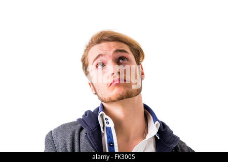 Attractive young man thinking, looking up with hand on his chin, isolated on white background, with doubtful expression Stock Photo