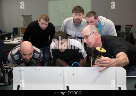 Adult men being taught engineering and pneumatics by qualified engineer instructor. Stock Photo