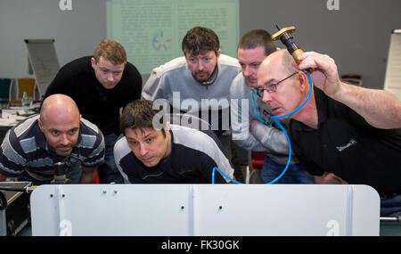 Adult men being taught engineering and pneumatics by qualified engineer instructor. Stock Photo