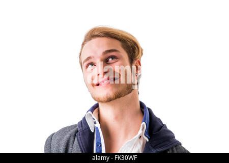 Attractive young man thinking, looking up with hand on his chin, isolated on white background, with doubtful expression Stock Photo