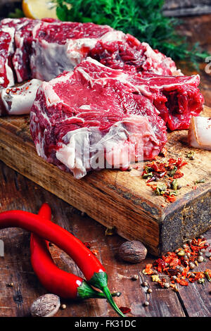 Chopped pieces of raw beef with spices on wooden cutting board Stock Photo