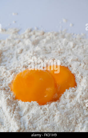 Two egg yolks on flour. Close view. Stock Photo