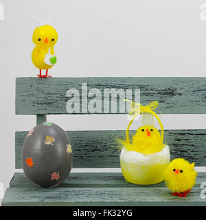 Composition with chick figurines and easter eggs, placed in a bench Stock Photo