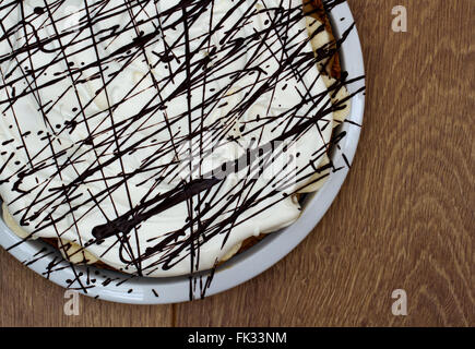 A Banoffee Pie with cream and chocolate on a wooden table. Stock Photo