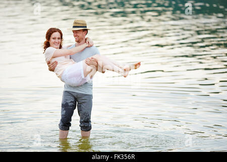 Happy man carrying smiling woman in water of a lake Stock Photo