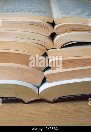A pile of open books on a wooden table Stock Photo