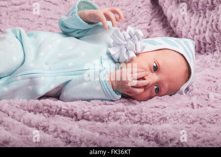 Humorous portrait of a baby girl covering her mouth with her tiny hand Stock Photo