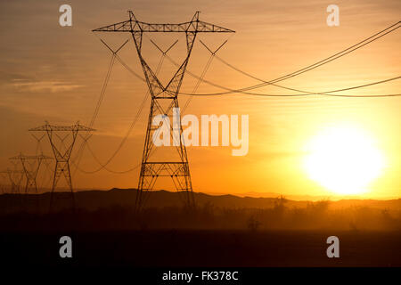 High tension power lines and the setting sun in the Sonoran Desert, California, USA Stock Photo