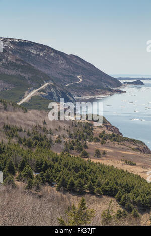 A vertical photo of a winding road that runs along the Atlantic Ocean, known as the Cabot Trail, in spring in Nova Scotia, east Stock Photo