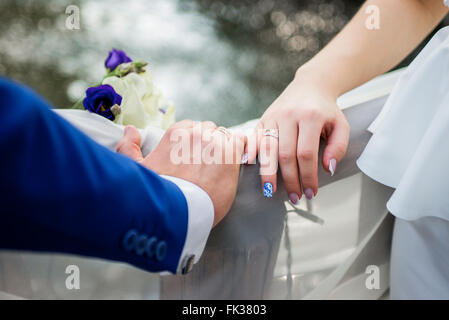 Hands and rings on wedding bouquet Stock Photo