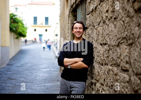 A young brunette dashing man standing in a traditional Sorrento street, Amalfi coast against an old, rustic wall Stock Photo