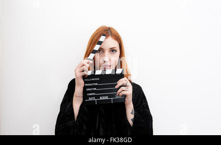 Young redhead woman portrait with black movie clapper board and copy space Stock Photo