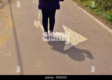 She stand outdoors by street with arrow pointing right Stock Photo