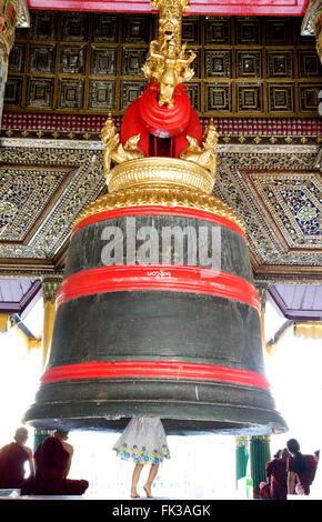 girl under a bell at Shwedagon Pagoda, tourist attraction in Yangon Stock Photo