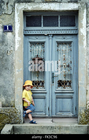 Portrait of a cute little kid leaning on a retro door Stock Photo