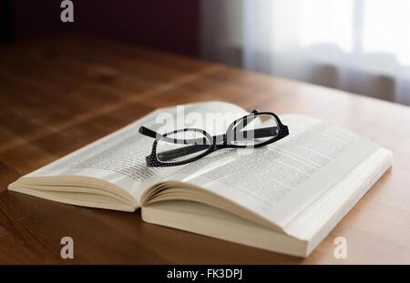 A pair of glasses on top of a book. Stock Photo