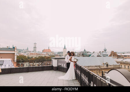 African wedding couple on the rooftop. Amazing european Lviv architecture on background Stock Photo