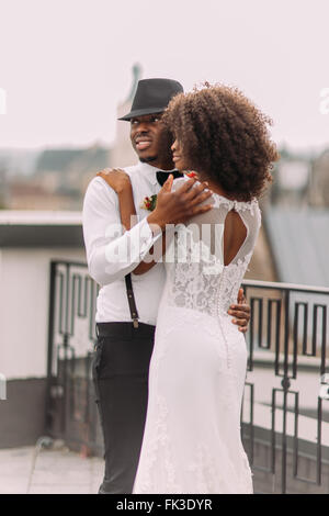 Beautiful black newlyweds softly hugging on the rooftop Stock Photo