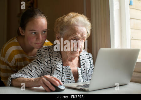Granddaughter teaches her grandmother to type on the laptop. Stock Photo