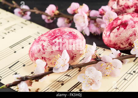 Decorated Easter eggs and fresh cherry blossom tree on sheet lines Stock Photo