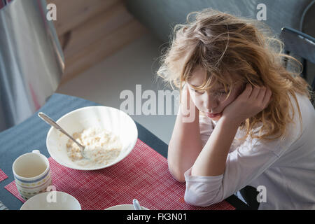 Little blond Caucasian sleepy girl has a breakfast Stock Photo