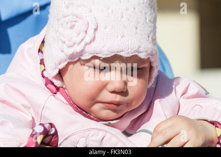 Little baby girl in pink crying, closeup outdoor portrait Stock Photo