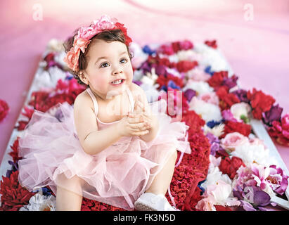 Cute girl sitting on a bunch of flowers Stock Photo