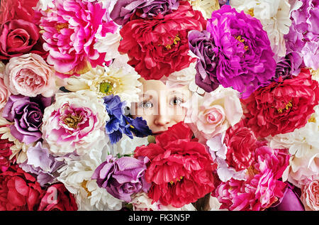 Conceptual picture of little girl behind a flower wall